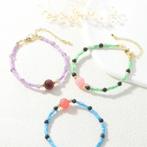 Detailed close-up of macaron color beaded bracelets with natural stones and gold lobster clasp