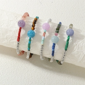 Detailopname van kleurrijke halfedelsteen armbanden met zilveren accenten op witte achtergrond
