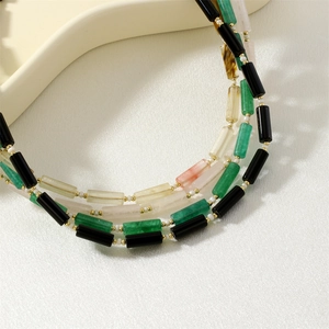 Detailed macro view of multi-colored beaded necklace with gold spacers and cylinder beads