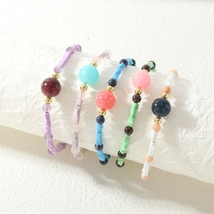 Detailed view of colorful macaron bead bracelets with gold accents on a white roll
