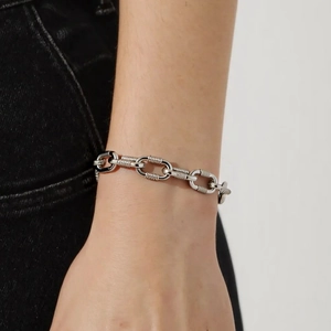Close-up of industrial heavy metal link bracelet with textured silver chain on wrist