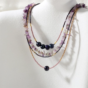 Close-up detail of multi-strand amethyst crushed stone, dark pearl and seed bead necklace.
