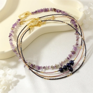 Detailed shot of natural amethyst chip seed bead and pearl layered necklace set with gold hardware.
