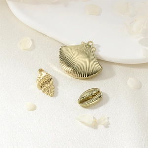 Pendentifs en métal doré en forme de coquillage sur fond de soie crème