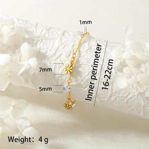 Detail view of gold daisy bracelet with faceted zircon accents on a textured surface