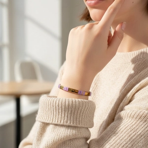 Bracelet TILA minimaliste violet et doré au poignet avec un tricot élégant