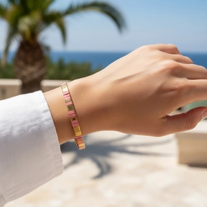 Gros plan d'un bracelet en tuiles roses et dorées porté par un mannequin dans un complexe