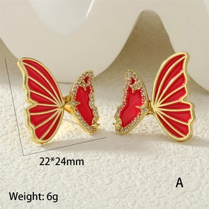 Macro view of gold-plated butterfly earrings with red enamel and zircon star details