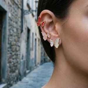Close-up of elegant gold butterfly earrings with colorful enamel and sparkling crystals