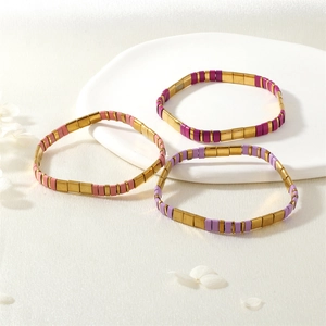 Vue détaillée de trois bracelets en perles Tila colorées sur un plateau en céramique