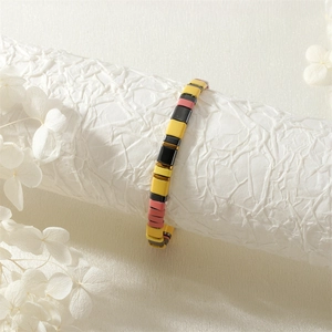 Détail d'un bracelet en perles Tila bohème avec carreaux jaunes, roses et dorés