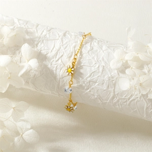 Detail of gold daisy bracelet with clear zircon crystals on elegant floral background