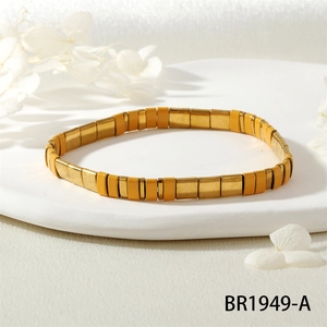 Gros plan détaillé du bracelet extensible Tila doré et jaune sur un plateau blanc