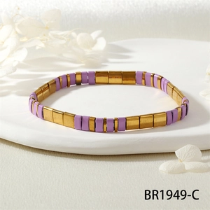 Détail du bracelet en perles Tila avec glaçure violette et accents dorés sur un plateau