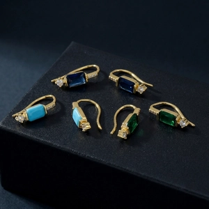 Gros plan de trois boucles d'oreilles en zircone rectangulaire bleu et vert doré
