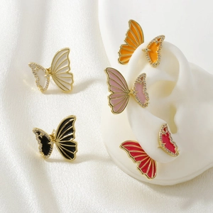 Macro detail of gold-plated butterfly earrings with colorful enamel and cubic zirconia