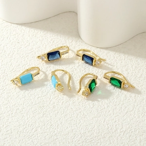Gros plan de boucles d'oreilles vintage en or avec zircons carrés vert émeraude et bleu