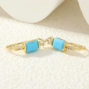 Détail macro de boucles d'oreilles dorées avec pierres turquoise et zircons blancs
