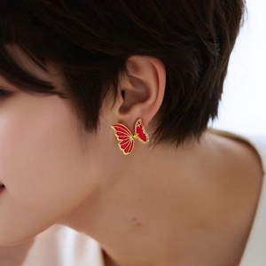 Macro shot of 18K gold butterfly earring with red enamel and shimmering rhinestones