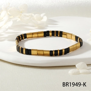 Détail du bracelet en perles TILA noires et dorées montrant la texture rectangulaire plate