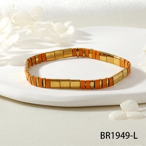 Gros plan détaillé du bracelet en perles Tila orange et or sur un plateau blanc