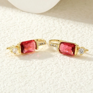 Détails de boucles d'oreilles dorées avec pierres rouges rectangulaires et zircons blancs