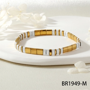 Vue détaillée du bracelet Tila minimaliste blanc et doré sur un support blanc décoratif