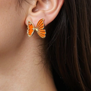 Detail of an orange butterfly earring with gold plating and sparkling zircon stones