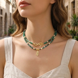 Close-up of emerald green beaded necklace with gold snake element and hollow pendant