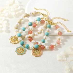 Detail of snake charm pendants on pearl and gemstone stretch bracelets in gold tone