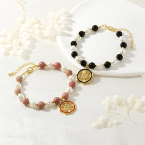 Detailed macro view of beaded pearl bracelets featuring gold snake charms and enamel finish