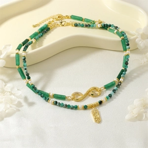 Detail of emerald gemstone and pearl necklace with golden snake clasp and vintage pendant
