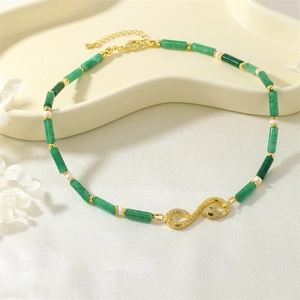 Close-up of emerald green beads and pearl necklace with a diamond snake pendant