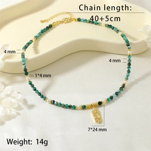 Detail view of emerald green beads, white pearls, and engraved golden pendant necklace