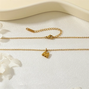 Détail du collier avec pendentif initiale M doré et étiquette K14 sur tissu blanc