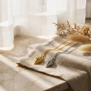 Close-up of 18K gold and silver seashell pendants with fine textures on linen