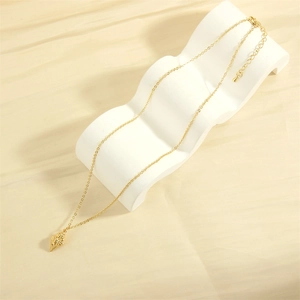 Macro detail of the 18K gold plated conch pendant on a cream textured silk background