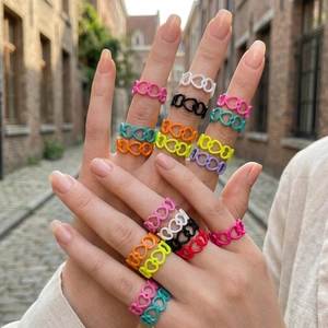 Colorful hollow heart-shaped rings in vibrant candy colors worn on a hand outdoors