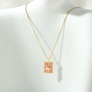 Detailed view of gold sword heart pendant with pink enamel and sparkling crystals
