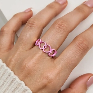 Close-up of pink enamel heart ring band with hollow macaron candy color design