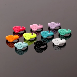 Detailed top view of colorful enamel smiley face open rings on a black reflective surface
