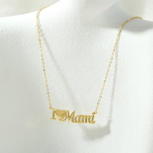 Close-up van gouden 'I Heart Mama' ketting met holle letters op een wit halsmodel