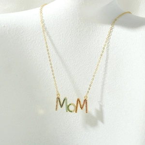 Detail van MOM letter hanger ketting met gekleurde zirkoonstenen op wit display
