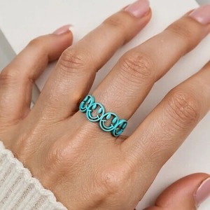 Close-up of turquoise matte enamel ring with hollow smiley face pattern on finger