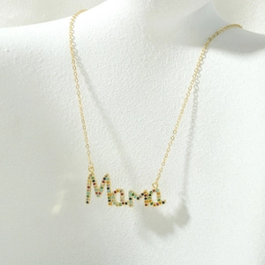 Detail van de gouden MOM-halsketting met gekleurde zirkoonstenen op modelhals