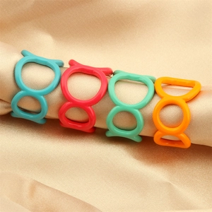 Close-up of matte heart smile rings in blue, red, green and orange on silk fabric