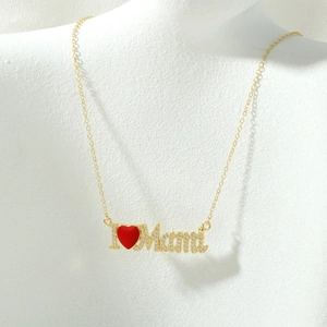 Macro-opname van gouden MOM-hanger met rood emaille hart en ingelegde zirkonia-stenen