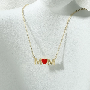 Macroweergave van gouden MOM-ketting met zirkonia-letters en een rode hart hanger