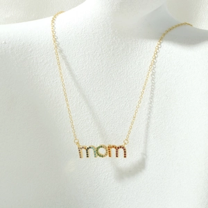 Detail van de gouden MOM-hanger met regenboog zirkonia stenen aan een fijne ketting