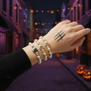 Close-up of Halloween bracelets with skulls and pearls worn on a wrist in night street